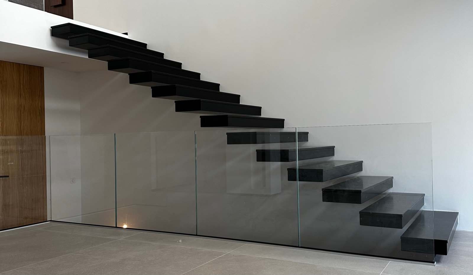 Escalier suspendu métallique noir et garde-corps en verre