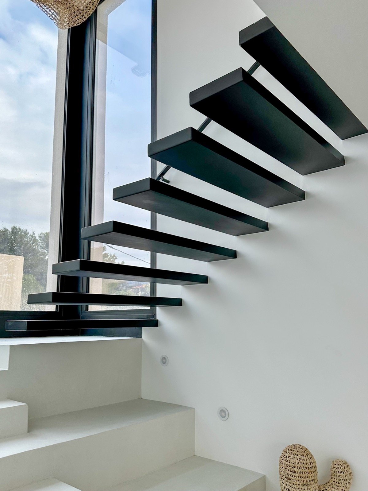 Escalier suspendu noir sur emmarchement béton