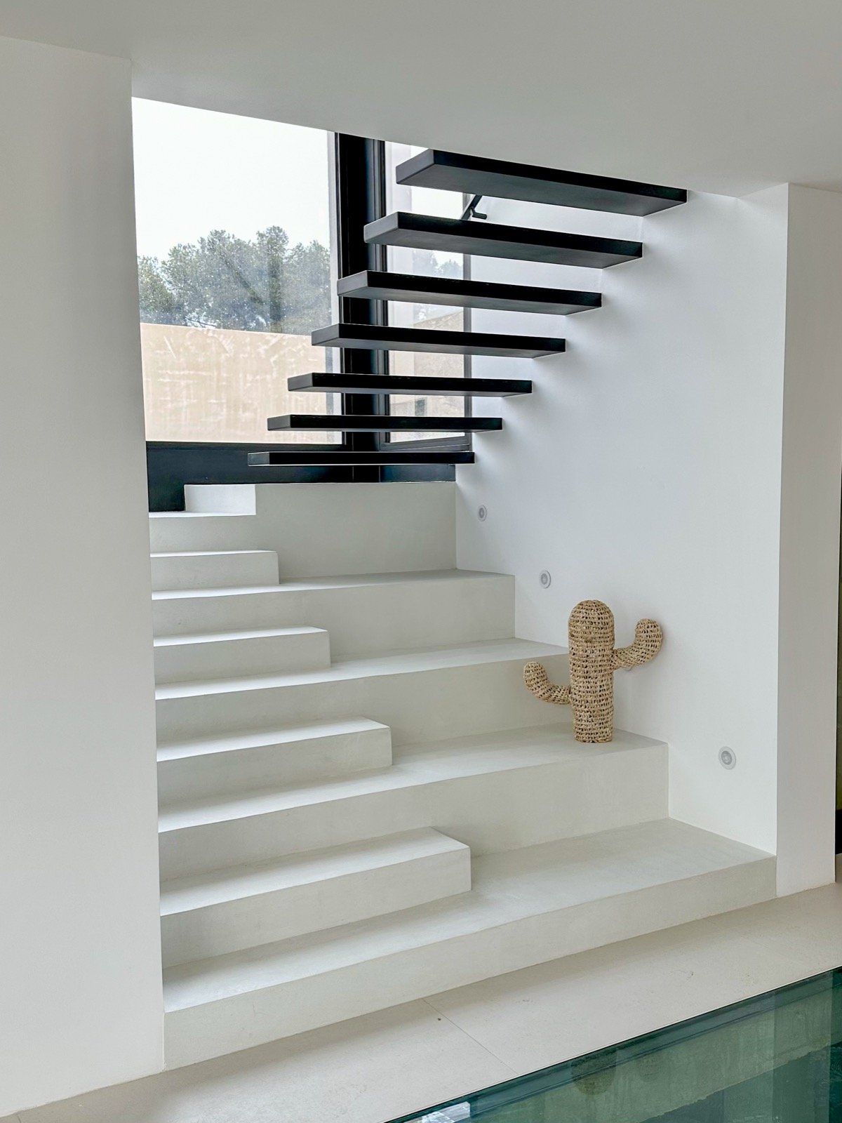 Escalier suspendu noir sur emmarchement béton